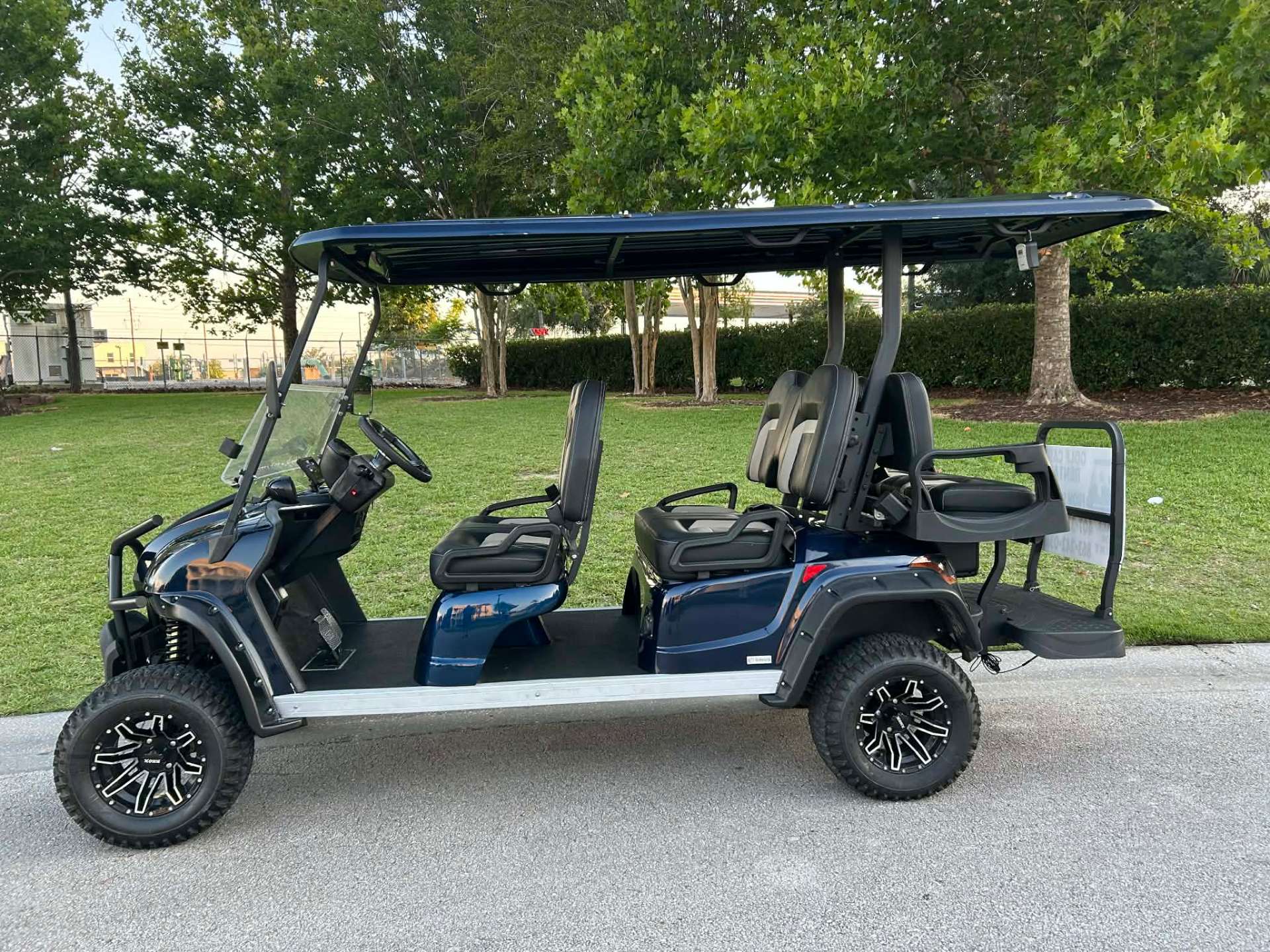 Navy blue 6-passenger luxury golf cart rental parked by a park
